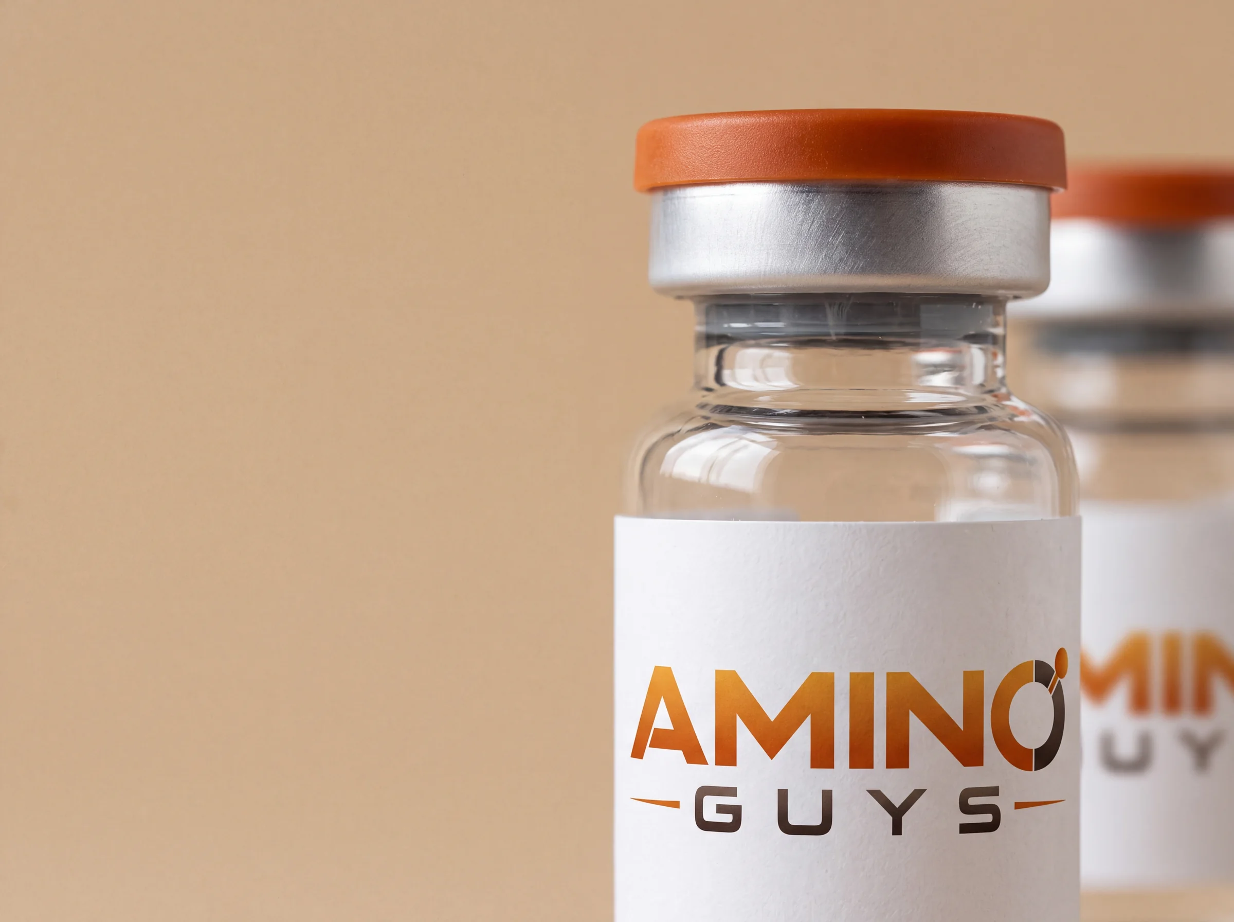 A close view of an Amino Guys labeled glass vial with a silver crimp and orange cap